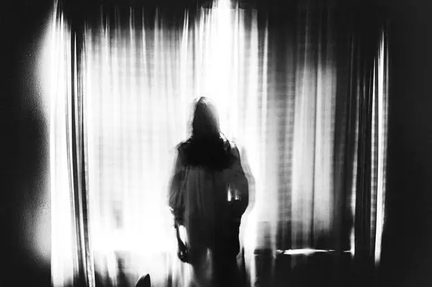 0 spooky image of ghost girl standing in window in eery light • mundo sombrio