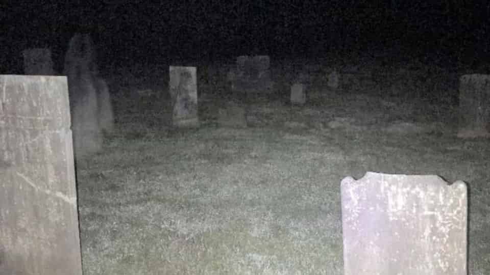 Imagem arrepiante mostra 'fantasma' espreitando sobre túmulo de cemitério mundo sombrio