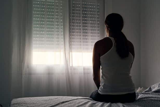 Mulher é aterrorizada em casa nova por fantasma de menina que se recusa a ir embora 4 0 rear view of an unrecognizable abused woman sitting on her bed looking out the window • mundo sombrio