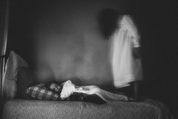 0 side view of spooky girl standing by sleeping sister on bed against wall at home • mundo sombrio